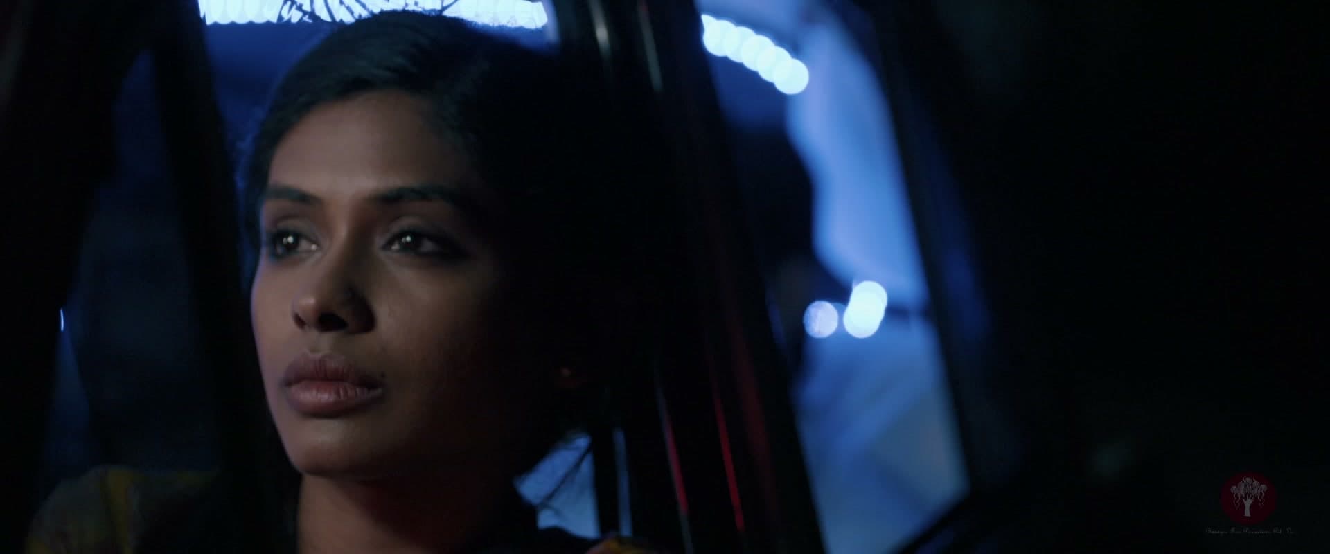 Iti in the back of the taxi, lit by blue light